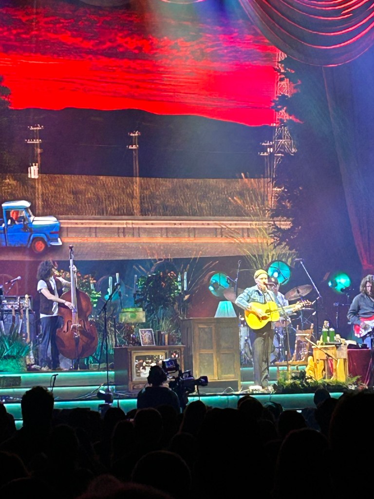 Best San Diego Music Venues; image showing Tyler Childers on stage with his band and many odds and ends. On the screen behind, there is a blue truck driving down a road.